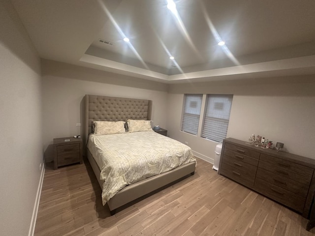 bedroom featuring hardwood / wood-style floors and a raised ceiling