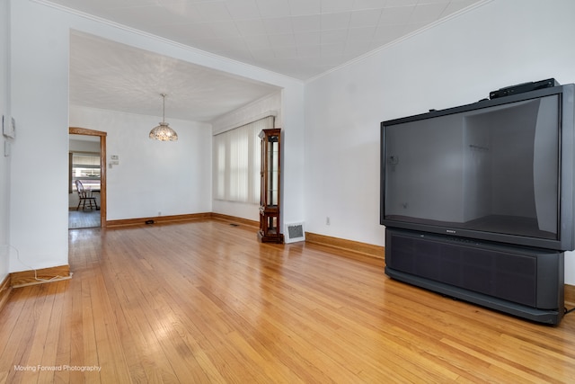 unfurnished living room featuring ornamental molding, an inviting chandelier, and hardwood / wood-style floors