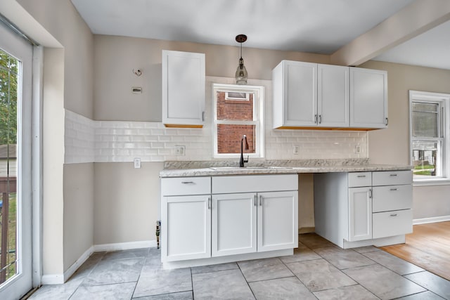 kitchen featuring light hardwood / wood-style floors, pendant lighting, sink, backsplash, and white cabinets