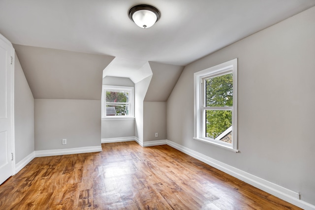 bonus room featuring plenty of natural light, vaulted ceiling, and light wood-type flooring