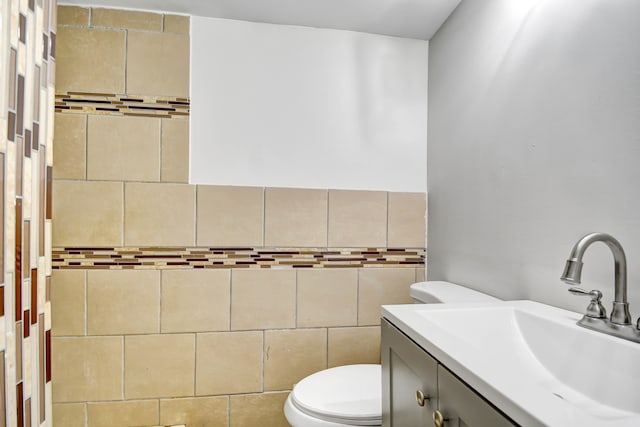 bathroom with vanity, tile walls, and toilet