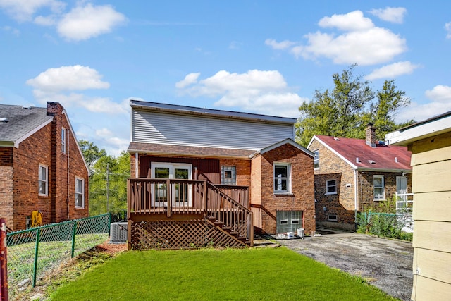 rear view of house featuring central AC unit and a yard