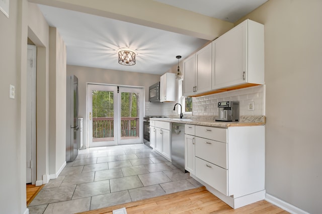 kitchen with appliances with stainless steel finishes, light wood-type flooring, pendant lighting, and white cabinets