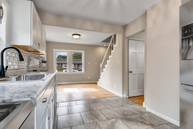 kitchen featuring stove, tasteful backsplash, sink, light hardwood / wood-style floors, and white cabinetry