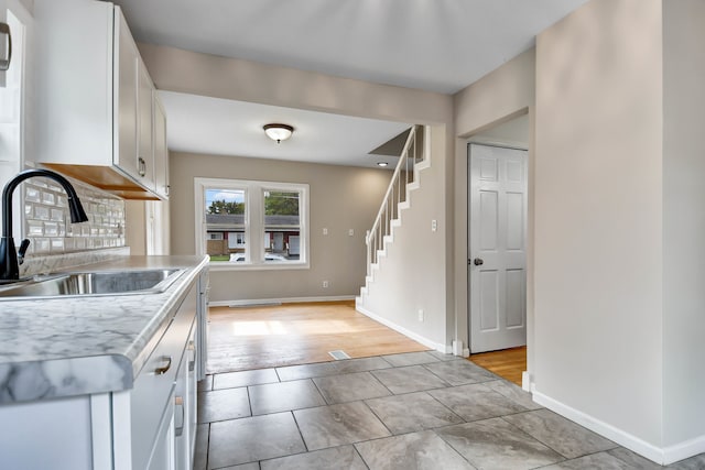 kitchen with tasteful backsplash, light hardwood / wood-style floors, white cabinets, and sink