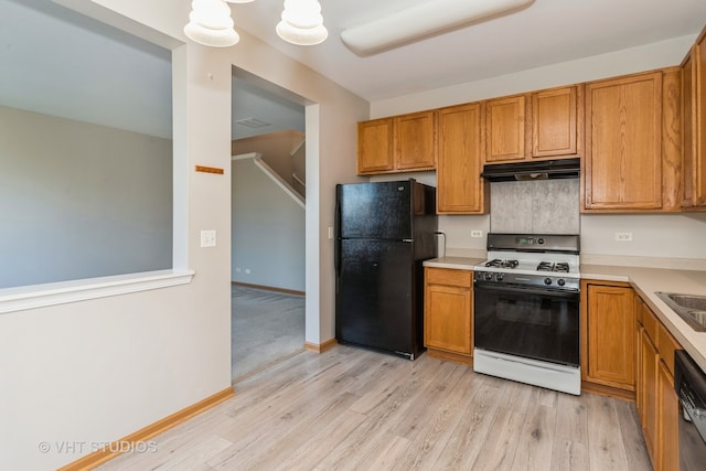 kitchen featuring dishwasher, black refrigerator, white gas range oven, sink, and light wood-type flooring