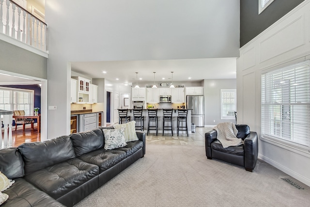 living room featuring a towering ceiling and light colored carpet