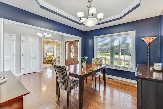 dining room featuring crown molding, a tray ceiling, and hardwood / wood-style floors