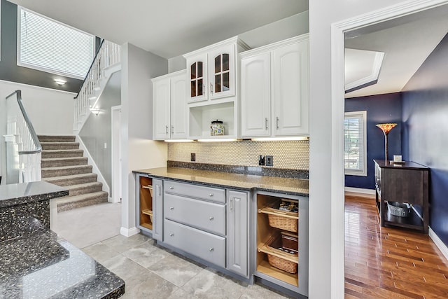 kitchen with tasteful backsplash, dark stone countertops, light wood-type flooring, and white cabinetry