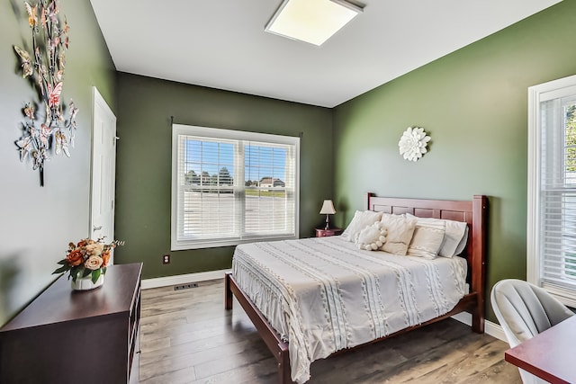 bedroom with multiple windows and dark hardwood / wood-style flooring