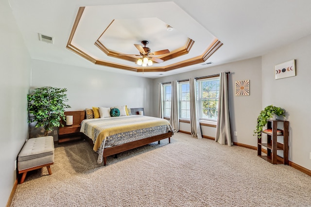 carpeted bedroom with ceiling fan, a raised ceiling, and ornamental molding