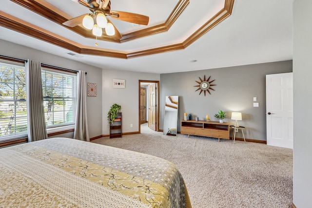 carpeted bedroom with ornamental molding, ceiling fan, and a tray ceiling