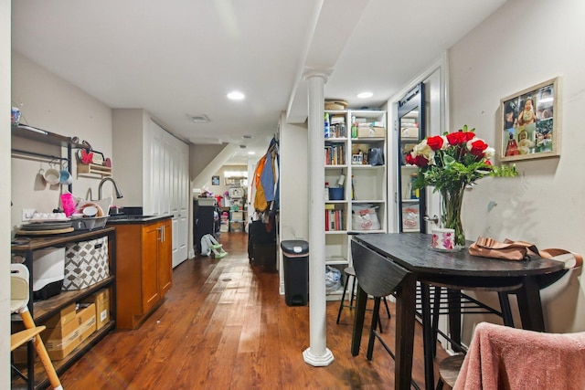 dining space featuring dark wood-type flooring, sink, and ornate columns