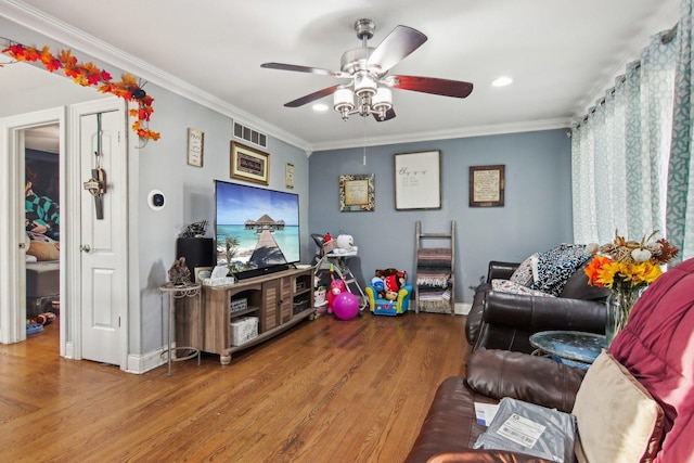 living room with visible vents, ornamental molding, wood finished floors, baseboards, and ceiling fan