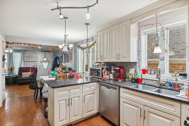 kitchen with wood finished floors, a peninsula, a sink, appliances with stainless steel finishes, and open floor plan