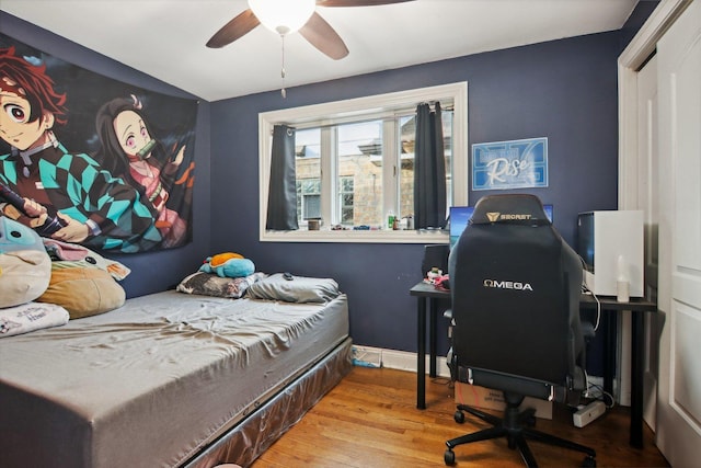 bedroom with ceiling fan, baseboards, and wood finished floors