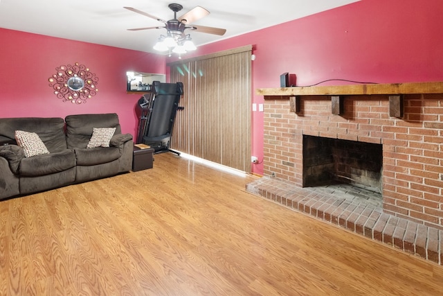 living room featuring ceiling fan, light wood-type flooring, and a fireplace