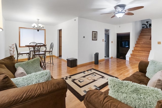 living room featuring ceiling fan with notable chandelier and light hardwood / wood-style floors