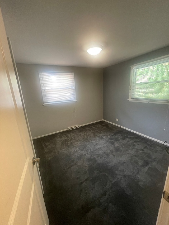 unfurnished room featuring dark carpet