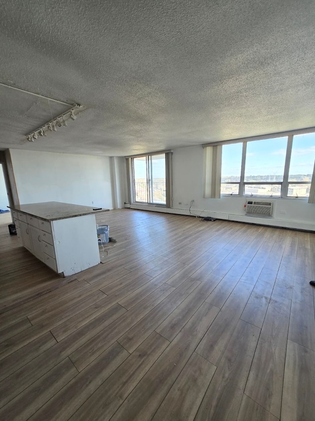 unfurnished living room featuring a textured ceiling, a wall mounted AC, and hardwood / wood-style flooring