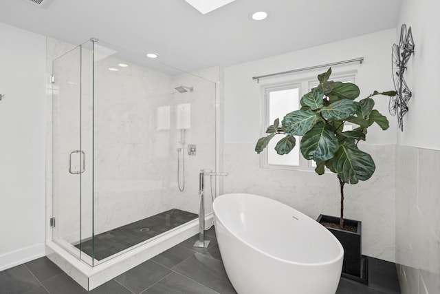 bathroom with plus walk in shower, tile patterned flooring, and tile walls