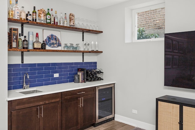 bar featuring dark brown cabinets, wine cooler, sink, and hardwood / wood-style floors