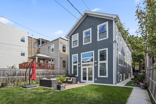 rear view of property featuring outdoor lounge area, a deck, a patio, and a lawn