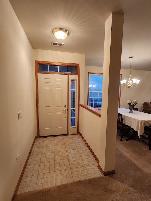 foyer featuring light colored carpet and a notable chandelier