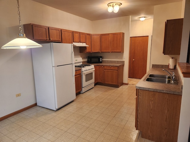 kitchen featuring white appliances, sink, and pendant lighting