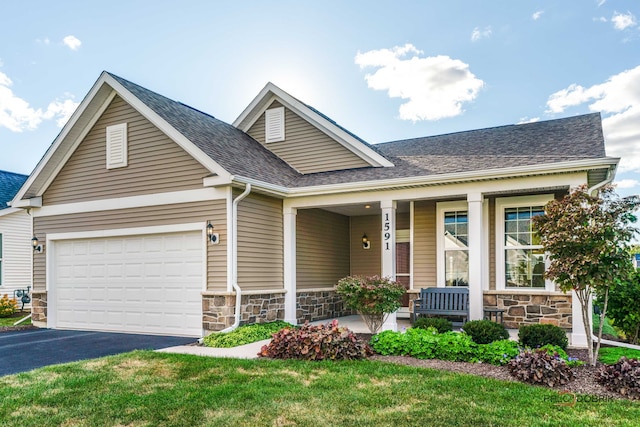 craftsman house featuring a porch, a front lawn, and a garage