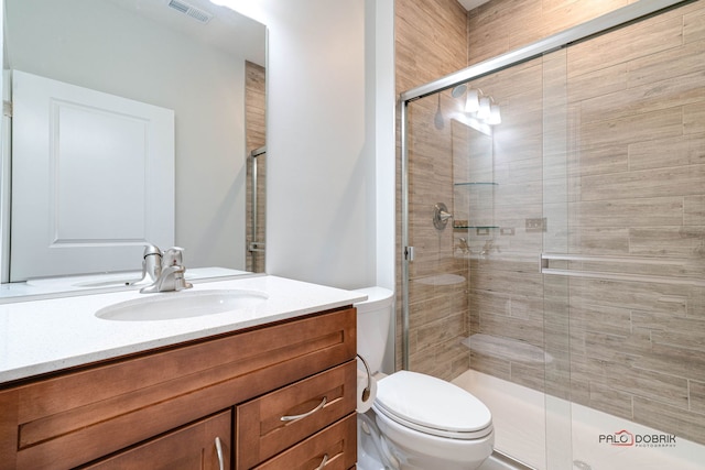 bathroom with vanity, a shower with shower door, and toilet