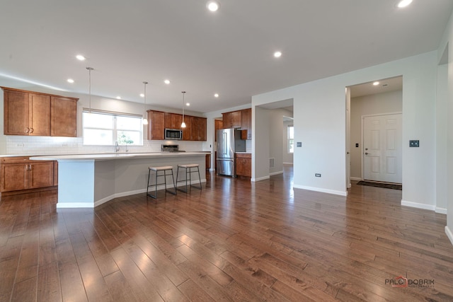 kitchen featuring appliances with stainless steel finishes, dark hardwood / wood-style floors, pendant lighting, and a kitchen island