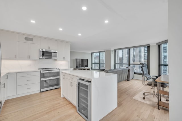 kitchen featuring appliances with stainless steel finishes, light hardwood / wood-style flooring, white cabinets, and beverage cooler