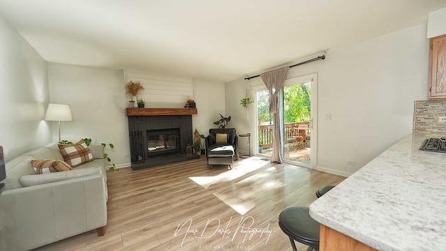 living room featuring a brick fireplace and light wood-type flooring