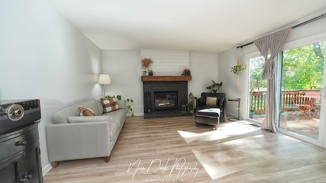 living room featuring a brick fireplace and light wood-type flooring