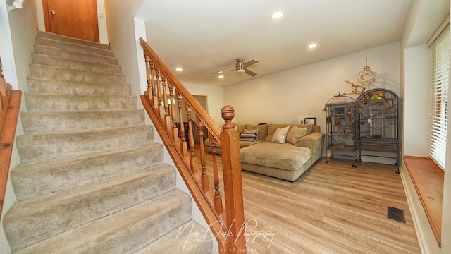 staircase featuring wood-type flooring and ceiling fan