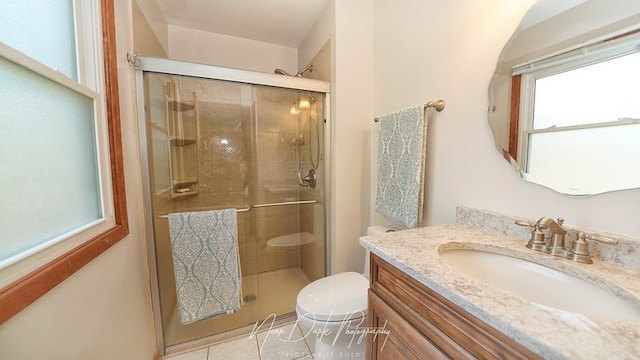 bathroom with tile patterned flooring, a shower with shower door, vanity, and toilet