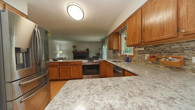 kitchen with light hardwood / wood-style floors, sink, stainless steel appliances, kitchen peninsula, and backsplash