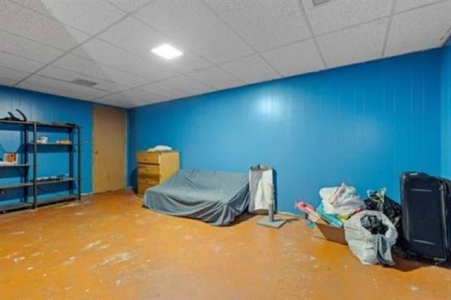 unfurnished bedroom with a paneled ceiling and concrete floors