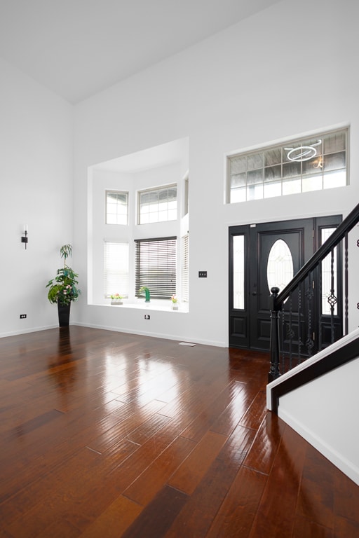 foyer entrance with a towering ceiling and dark hardwood / wood-style floors