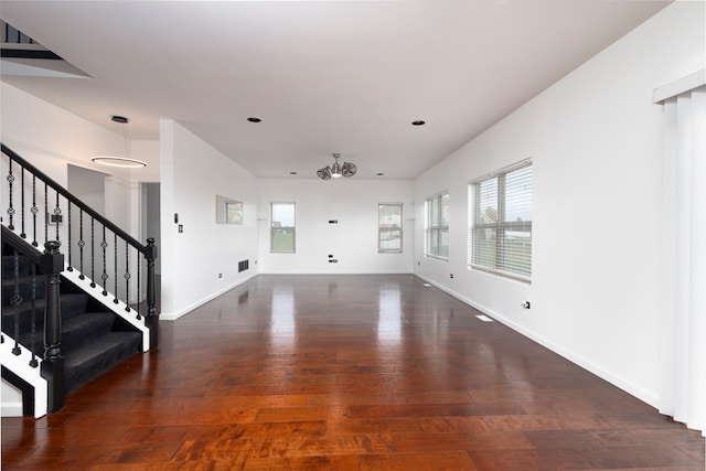 unfurnished living room featuring dark wood-type flooring and a notable chandelier