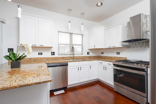 kitchen with dark hardwood / wood-style floors, wall chimney exhaust hood, stainless steel appliances, pendant lighting, and white cabinetry