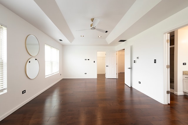 empty room featuring a raised ceiling, ceiling fan, and dark hardwood / wood-style flooring