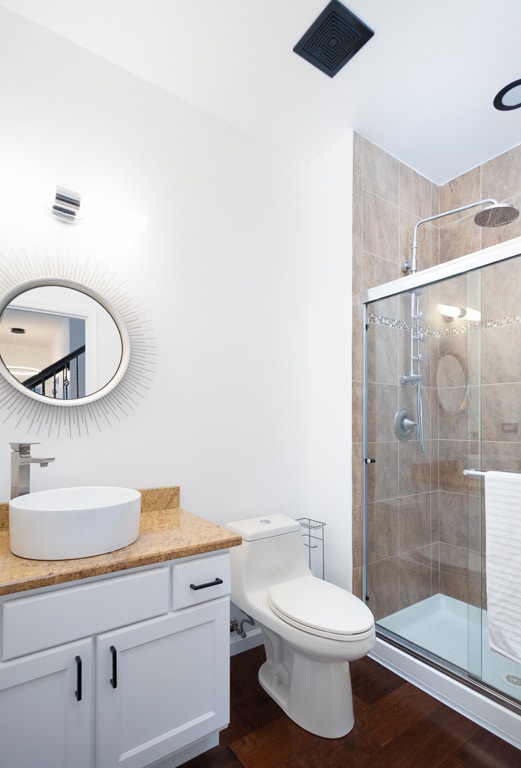 bathroom featuring vanity, toilet, a shower with shower door, and hardwood / wood-style floors