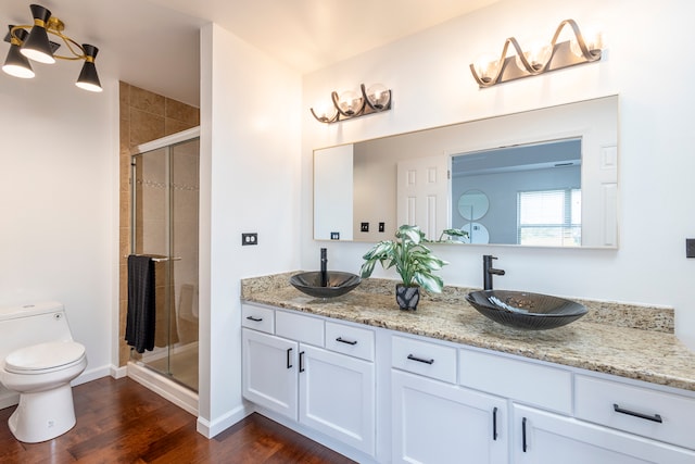 bathroom with toilet, hardwood / wood-style flooring, vanity, and a shower with door