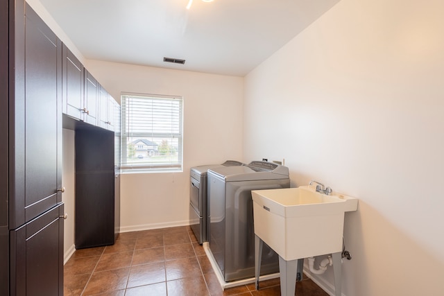 laundry room featuring sink, cabinets, washing machine and clothes dryer, and dark tile patterned floors