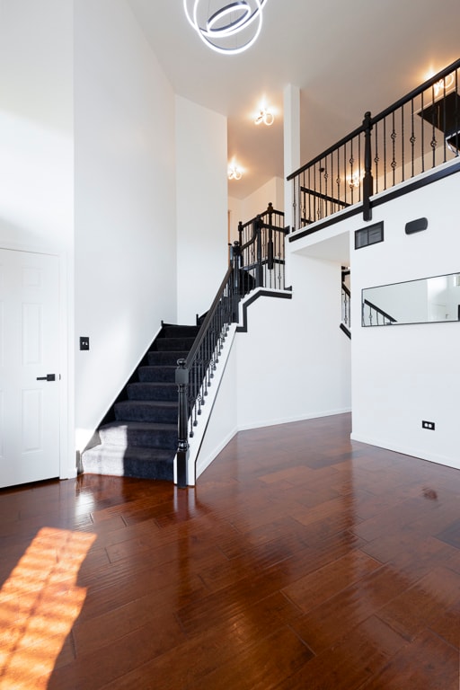 stairs featuring a towering ceiling and wood-type flooring