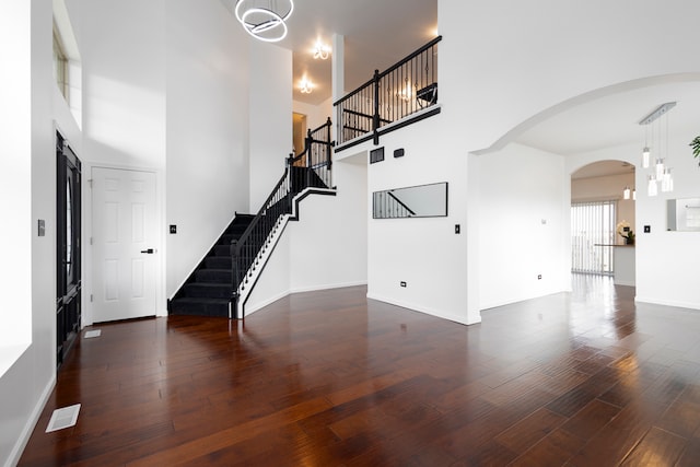 interior space with a towering ceiling and dark hardwood / wood-style flooring