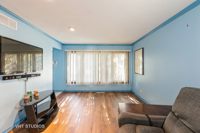 sitting room with hardwood / wood-style floors and crown molding