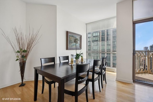 dining room with expansive windows, light hardwood / wood-style floors, and a wealth of natural light